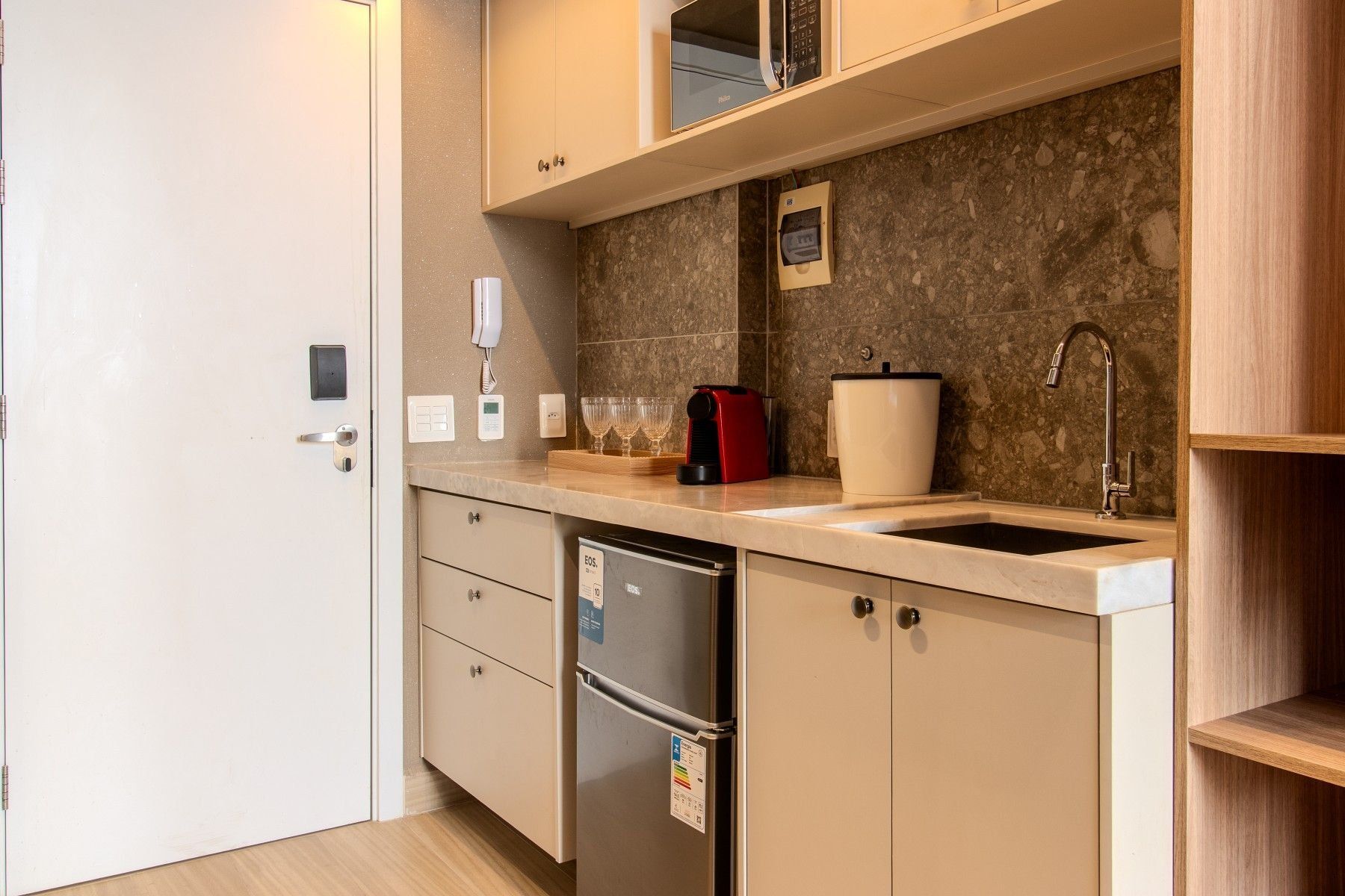 A compact kitchen with a refrigerator, a sink, a coffee maker, and a microwave.