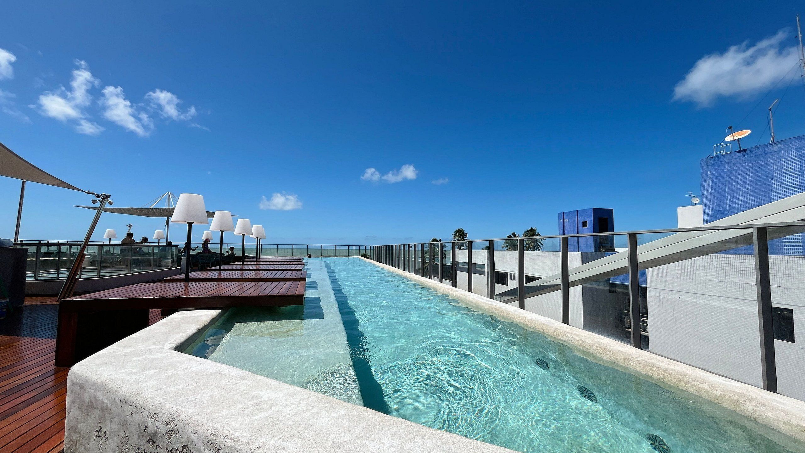 Ett poolområde med fri utsikt över havet, solstolar och en modern byggnadsstruktur.