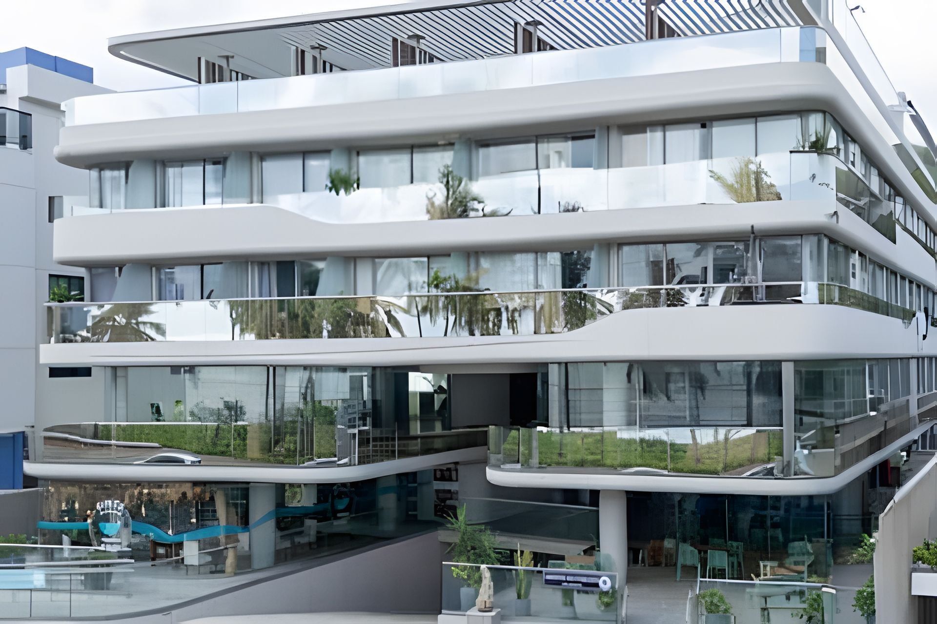 Un edificio de varios pisos con fachada de vidrio, balcones y zonas de estar al aire libre.