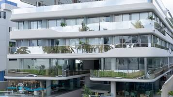 Un edificio de varios pisos con fachada de vidrio, balcones y zonas de estar al aire libre.
