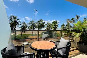 A balcony with a glass railing, a round wooden table, and black chairs.