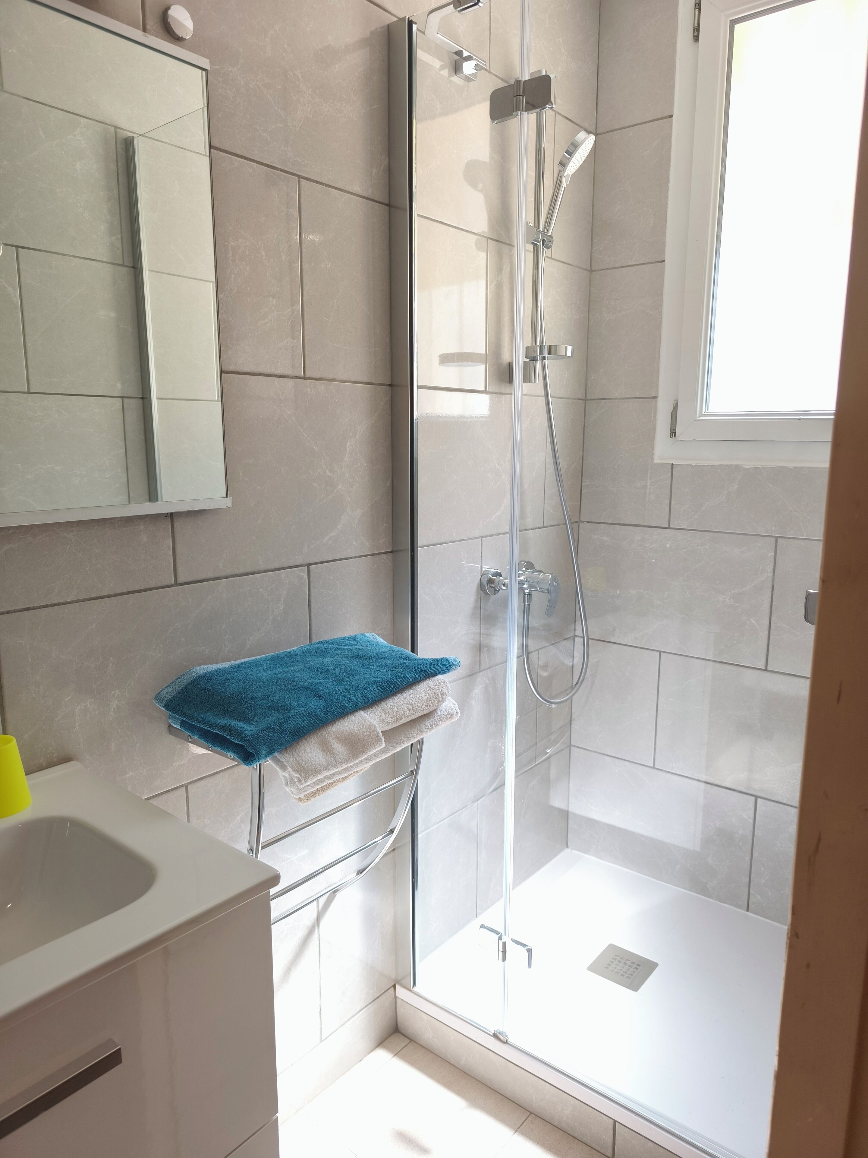 A modern bathroom with a glass-enclosed shower, a white sink, and a mirror.