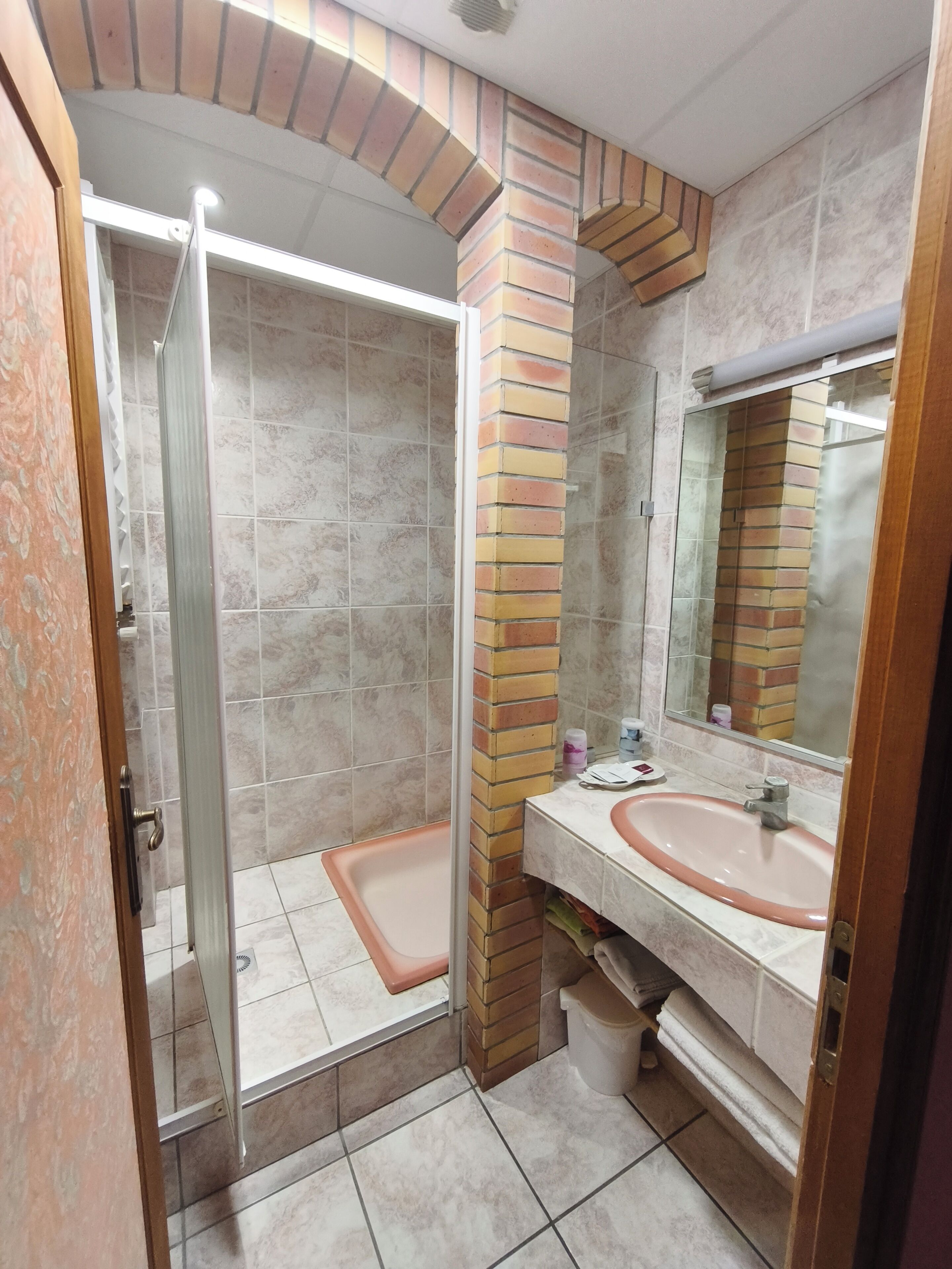Un baño con ducha envuelta en vidrio, lavamanos y espejo.