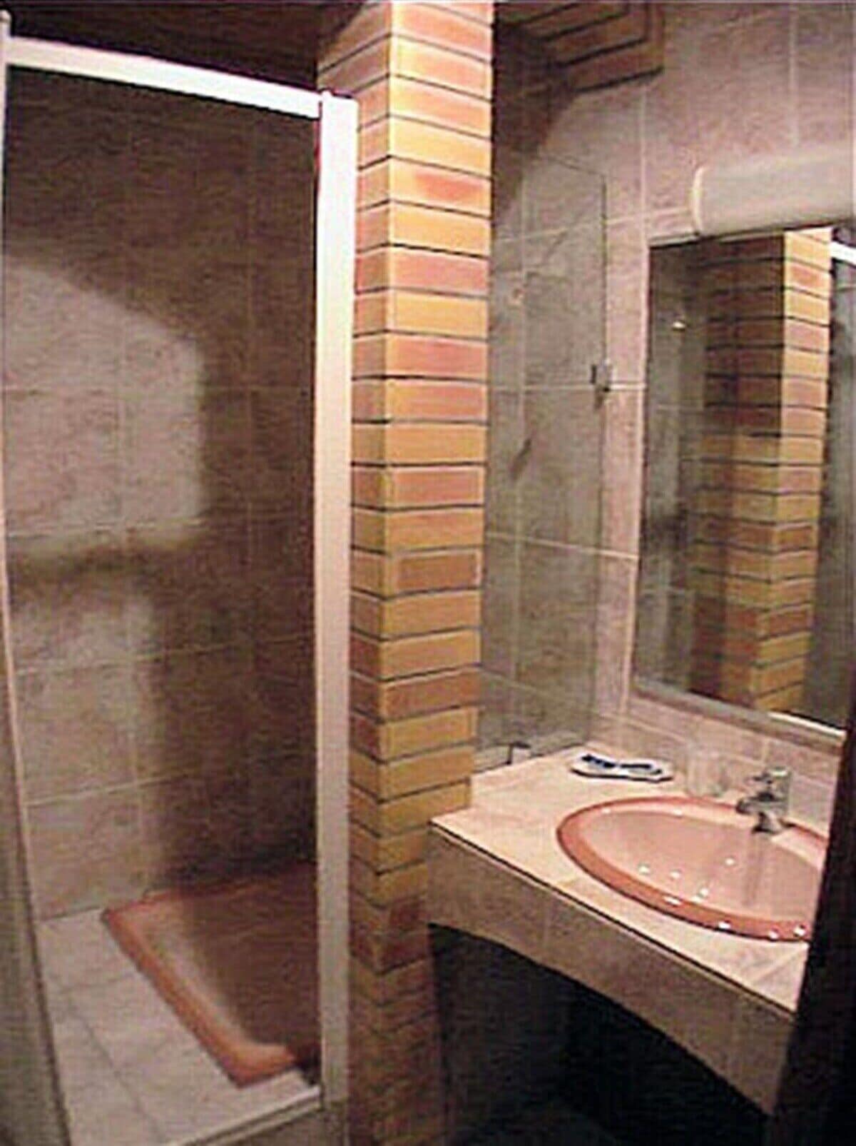 Un baño con cabina de ducha de vidrio, lavamanos y espejo.