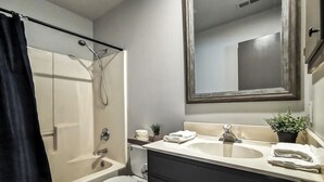Ein Badezimmer mit Badewanne, Toilette, Waschbecken und einem Spiegel darüber.