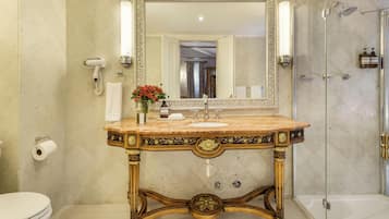 Un baño con lavamanos de mármol, un espejo grande y una ducha.