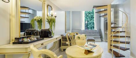 Une pièce comprenant une table à manger, des chaises, un grand miroir, une machine à café et un escalier.