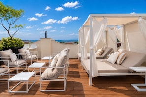 A rooftop terrace with outdoor seating, a canopy bed, and a view of the sea. - Hotel Bardot Boutique (Panama City)