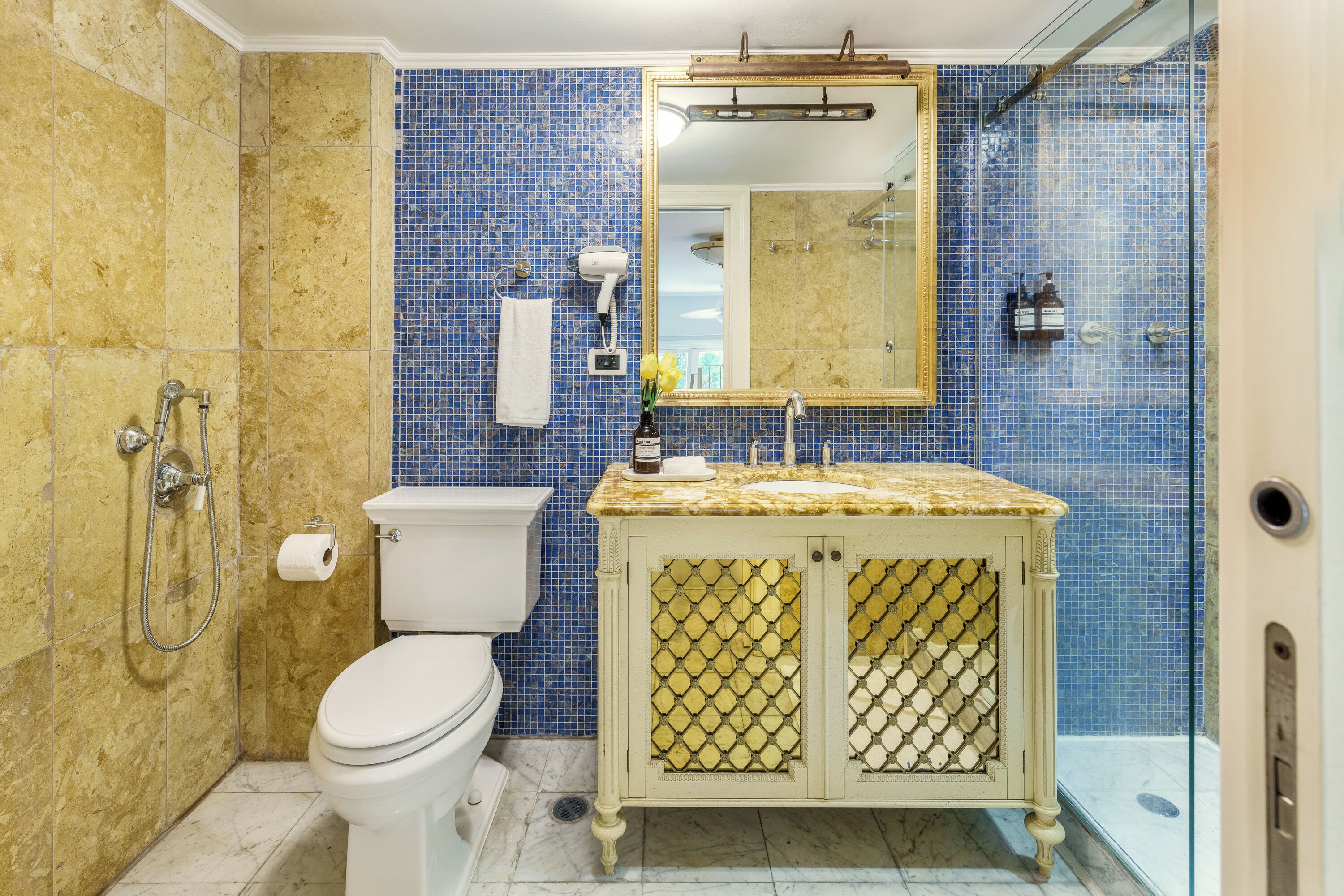Een badkamer met toilet, wastafel met spiegel en douchehoek.