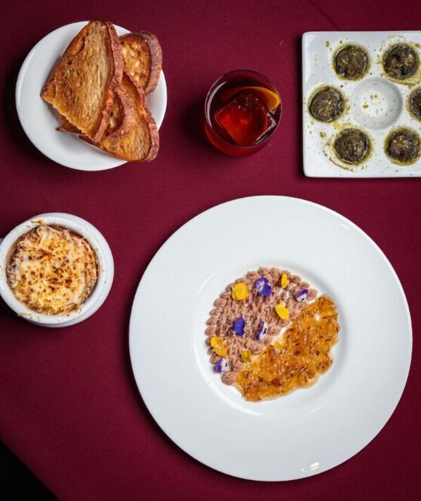Une table avec une assiette de nourriture, un bol de soupe et un verre contenant une boisson.