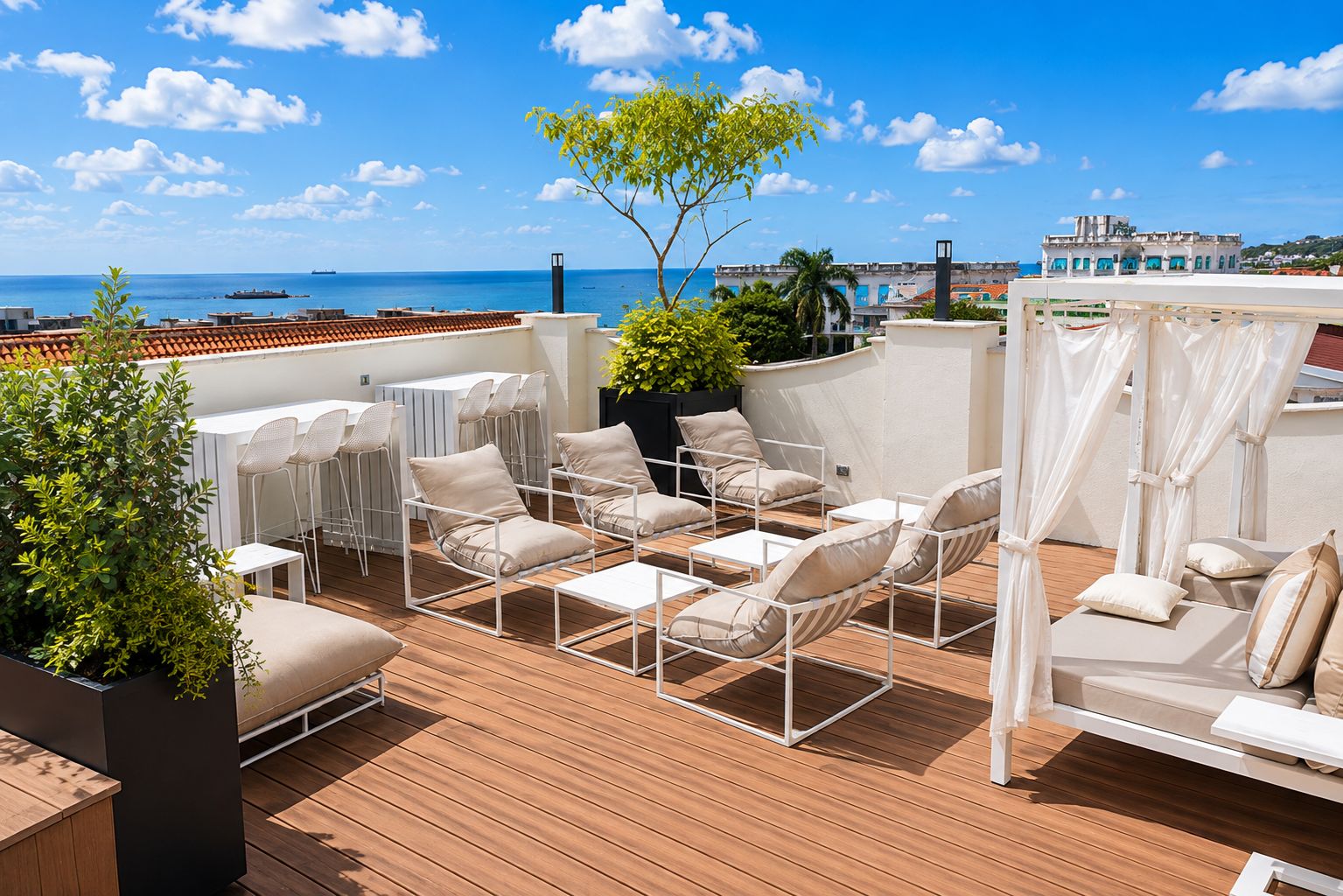A rooftop terrace with outdoor seating, a view of the sea, and a building in the background.
