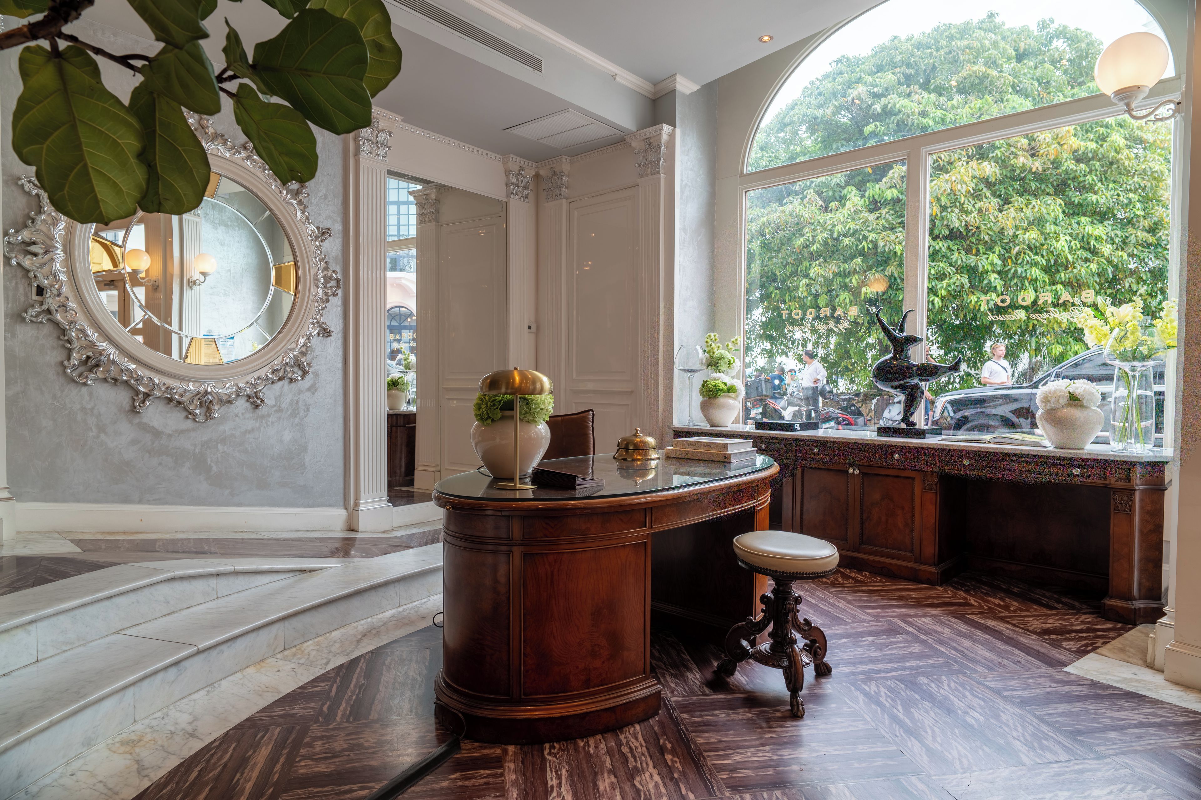 A spacious room with a large mirror, a wooden desk, and a view of the outdoors through a large window.