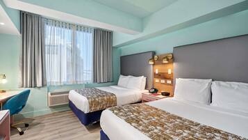 A hotel room with two beds, a desk, a chair, and a window with curtains.
