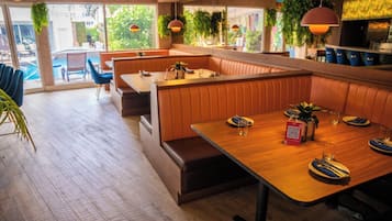 A restaurant with wooden tables and booths, large windows, and hanging plants.