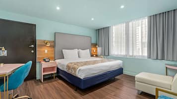 Une chambre d’hôtel moderne, dotée d’un grand lit, d’un bureau, d’une chaise et d’une fenêtre avec des rideaux.
