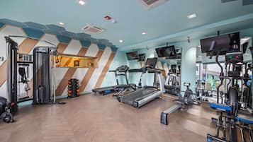 A gym with treadmills, weight machines, and a mirrored wall.
