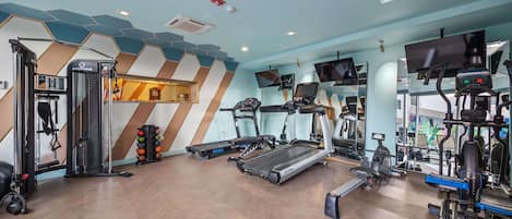 Un gimnasio con cintas de correr, máquinas de pesas y un espejo grande.