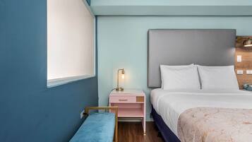 A bedroom with a bed, a bedside table with a lamp, a bench, and a window.