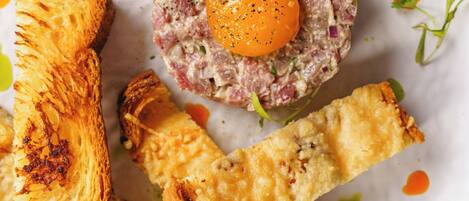 A plate with a meat-based dish, a fried item, and a crispy bread-like item.