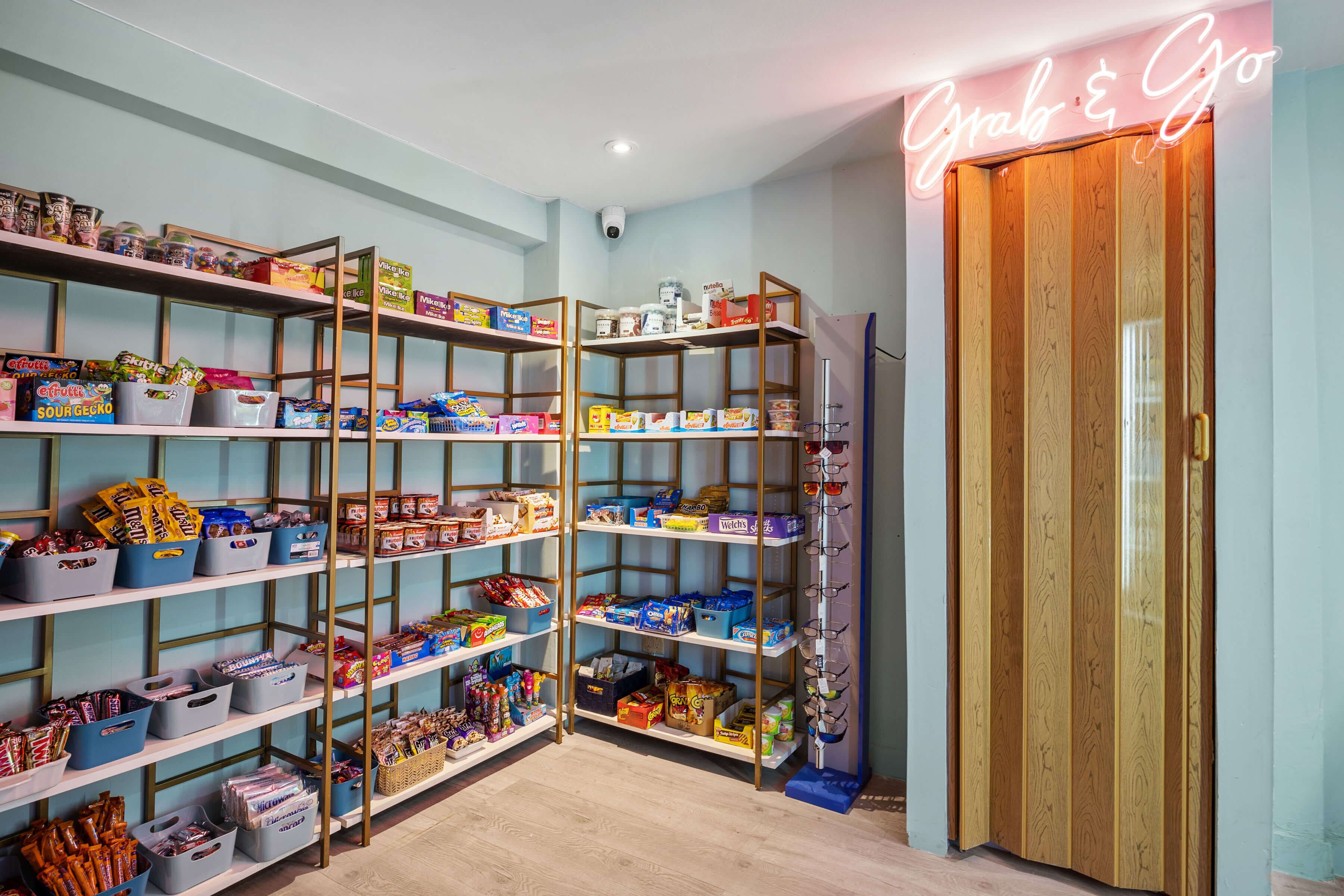 A well-organized pantry with multiple shelves stocked with various food items and a neon sign above the door.