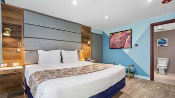 A modern hotel room with a large bed, wooden headboard, and a blue accent wall.