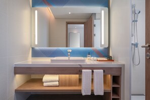 A modern bathroom with a large mirror, a sink, and a shower. There are towels and toiletries on the counter. - Holiday Inn Express Chongqing Liangjiang Yufu by IHG (Chongqing)