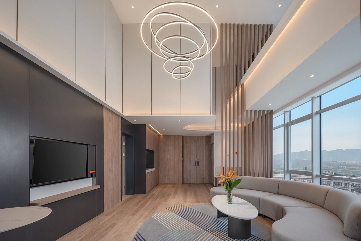 Una sala de estar moderna con un televisor de pantalla plana grande, un sofá curvo y un comedor con una mesa pequeña.