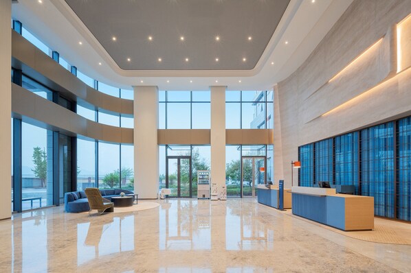 Un hall espacioso con mostrador de recepción, zona de estar y grandes ventanales con vistas al exterior.