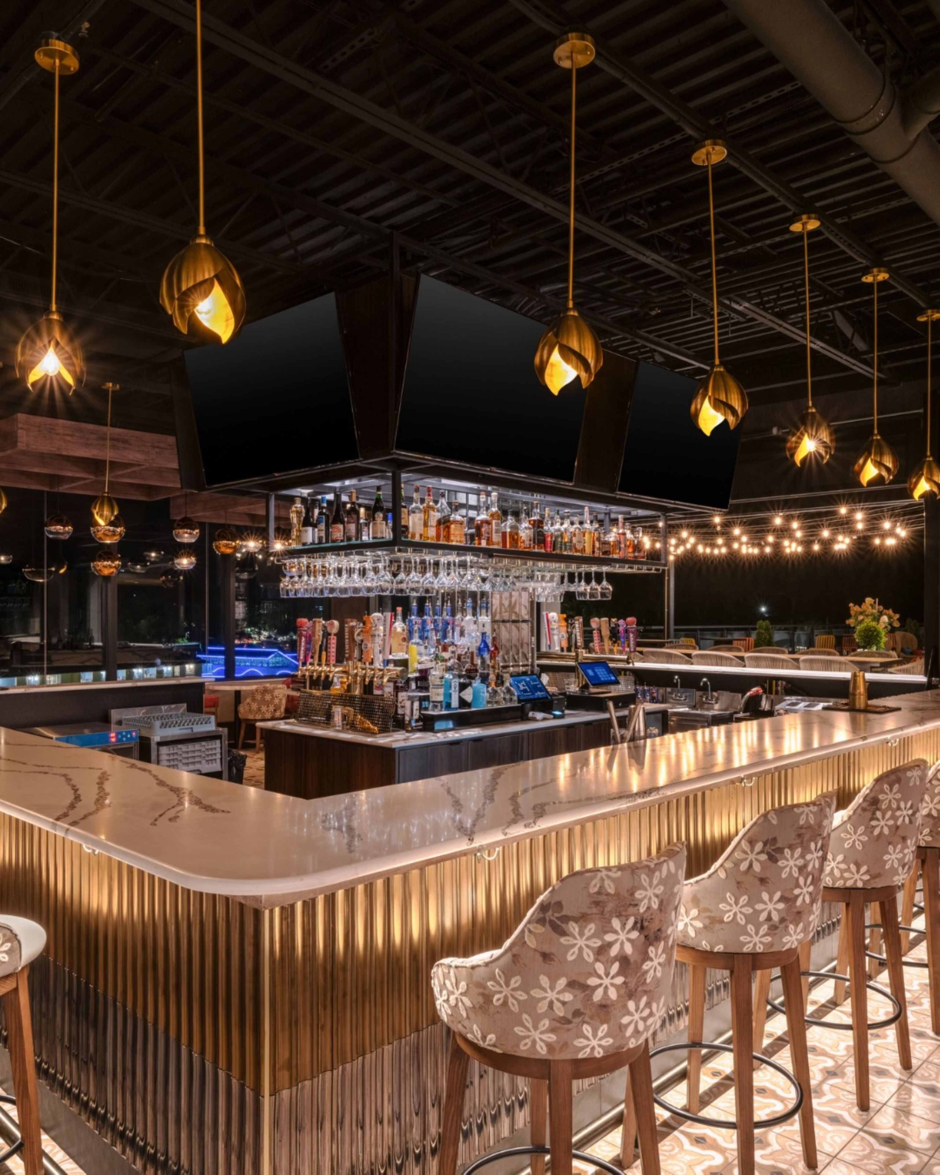A bar area with a counter, bar stools, and hanging pendant lights.
