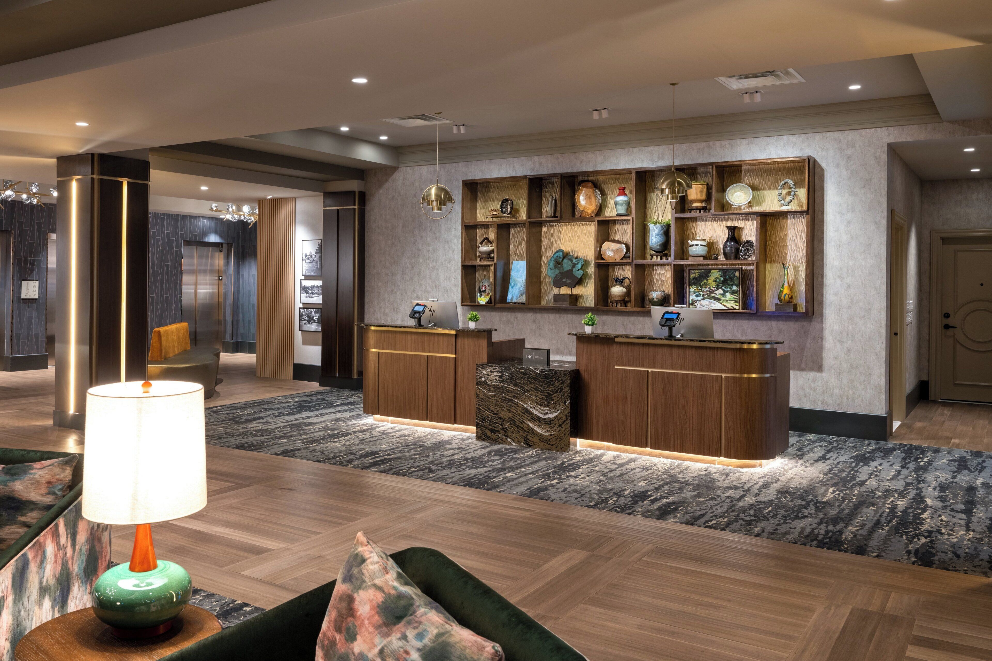 A modern reception area with a wooden reception desk, a green sofa, and a patterned rug.