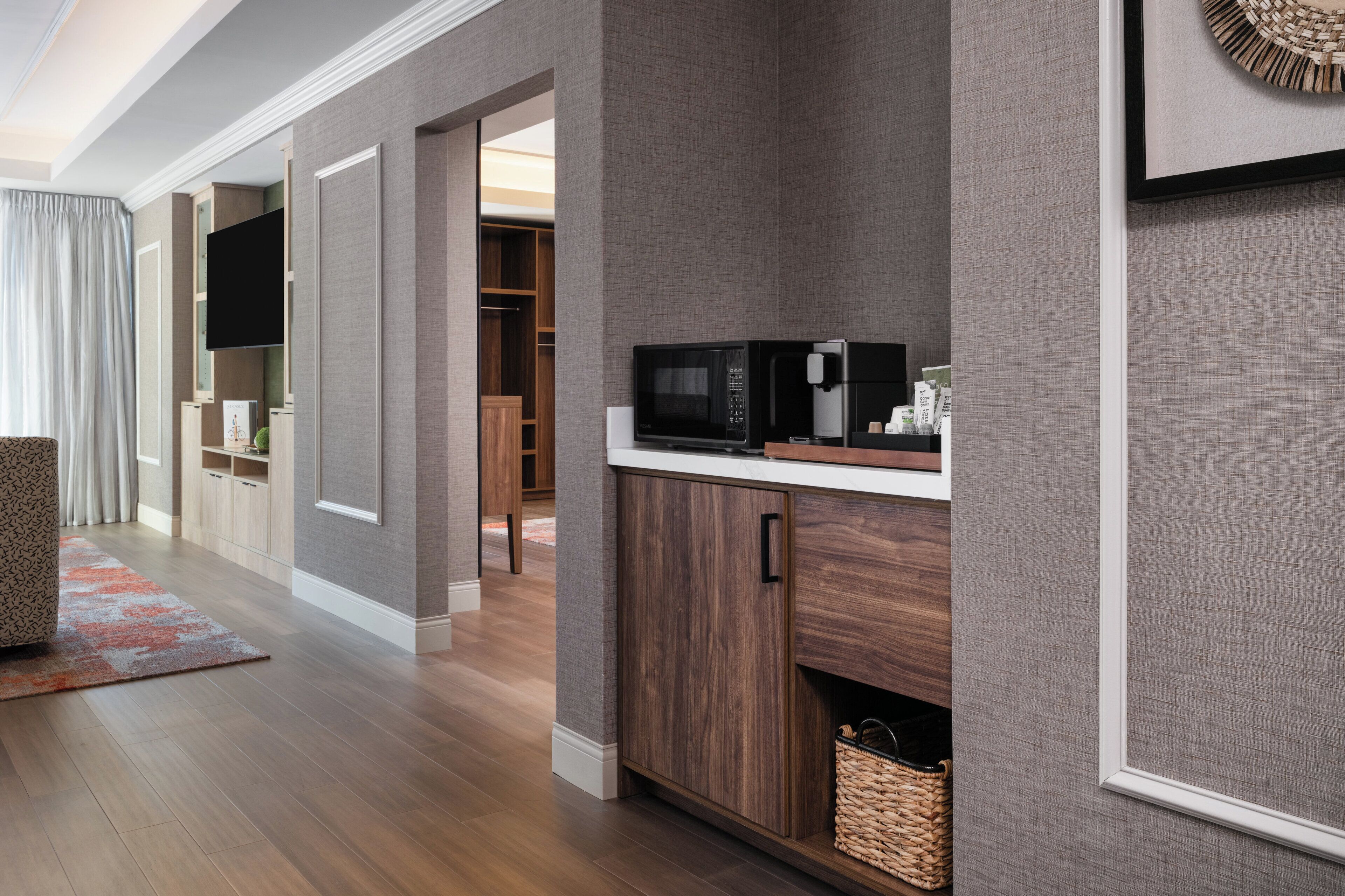 A modern kitchen with a microwave, coffee maker, and storage cabinets.