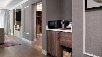 A modern kitchen with a microwave, coffee maker, and storage cabinets.