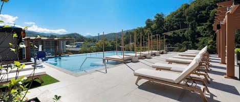 A rooftop pool area with lounge chairs and a view of a mountainous landscape.