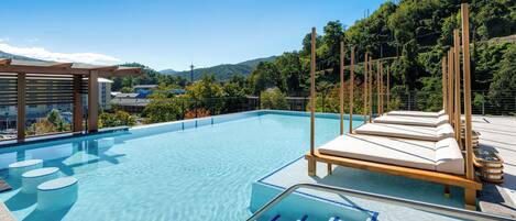 Ein klares, blaues Schwimmbecken mit Liegestühlen und einer Pergola.