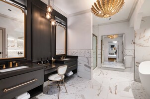 A modern bathroom with two sinks, a large mirror, and a gold chandelier.
