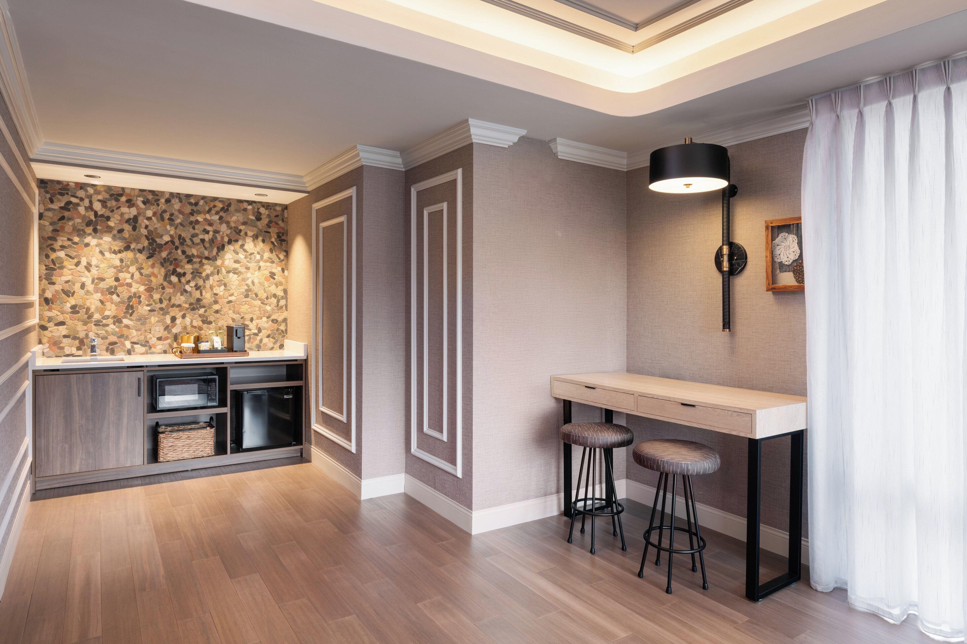 Eine moderne Küche mit Steinrückwand, Holdekor-Schränken, integriertem Mikrowellenherd und einer Bar mit Hockern.