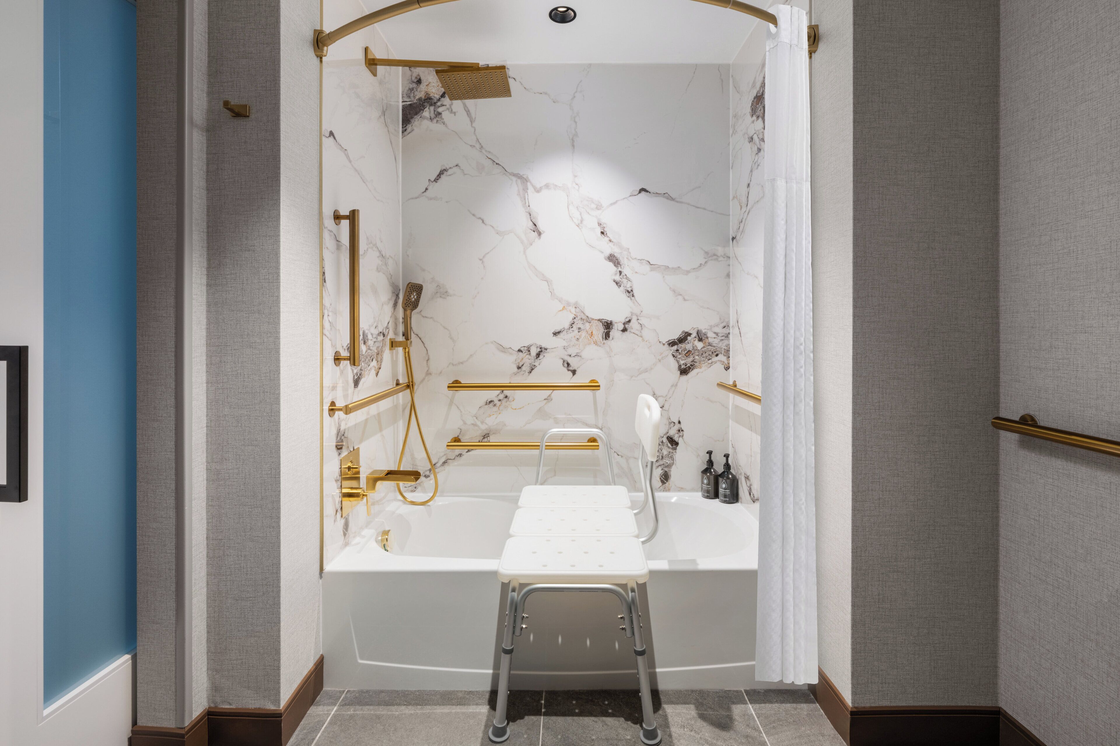 A modern bathroom with a marble wall, a bathtub, and a shower area.