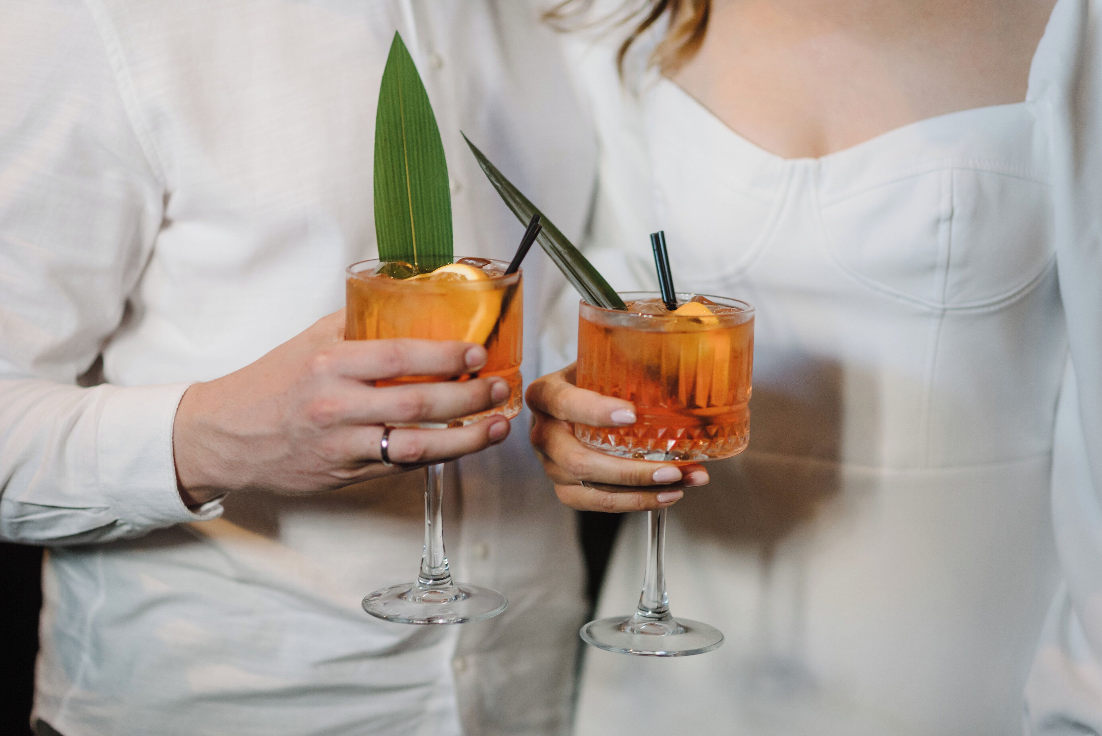 Deux personnes tenant des verres contenant une boisson, décorée d’une feuille.