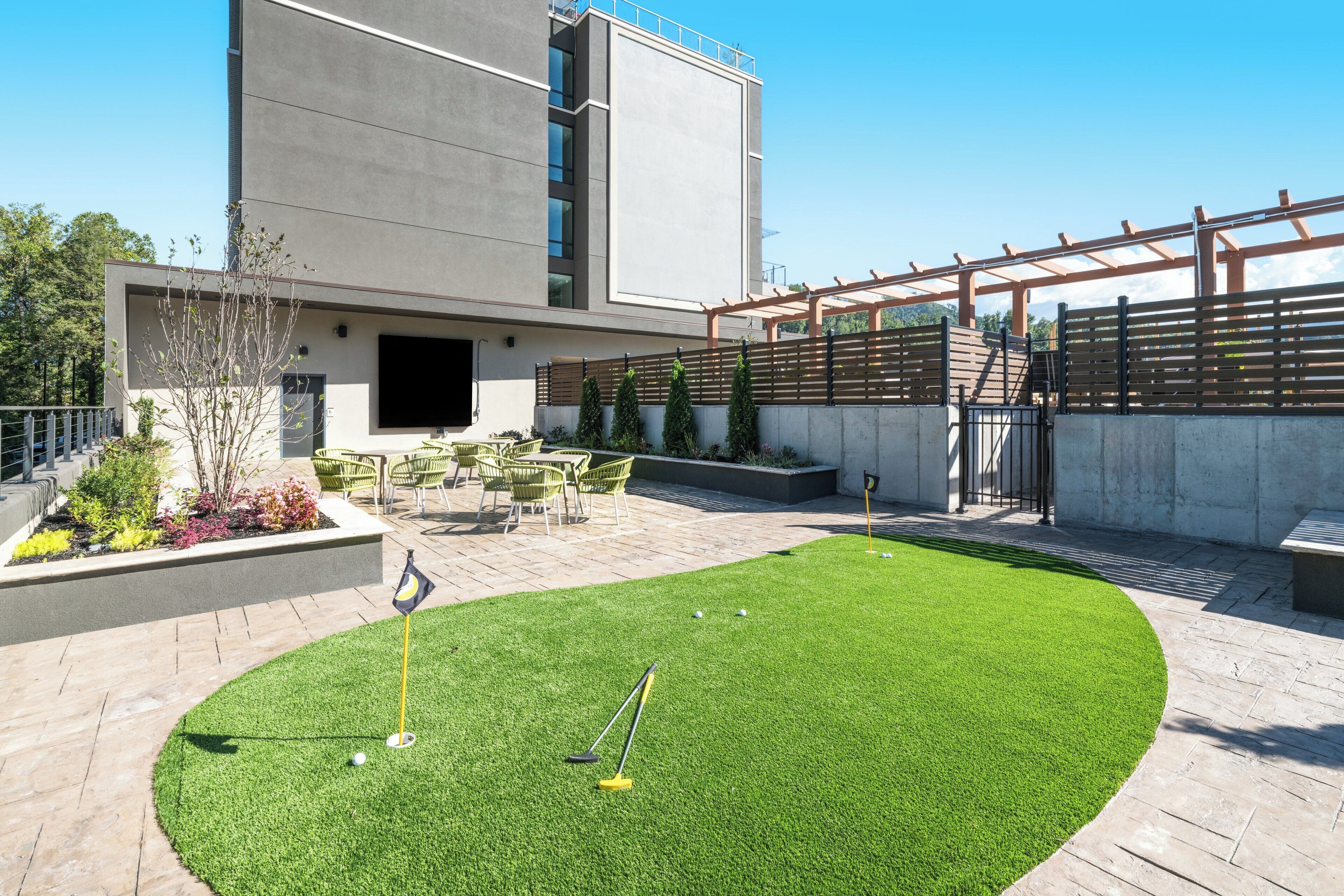 A modern building with a flat roof, a patio area with artificial grass, and outdoor seating.