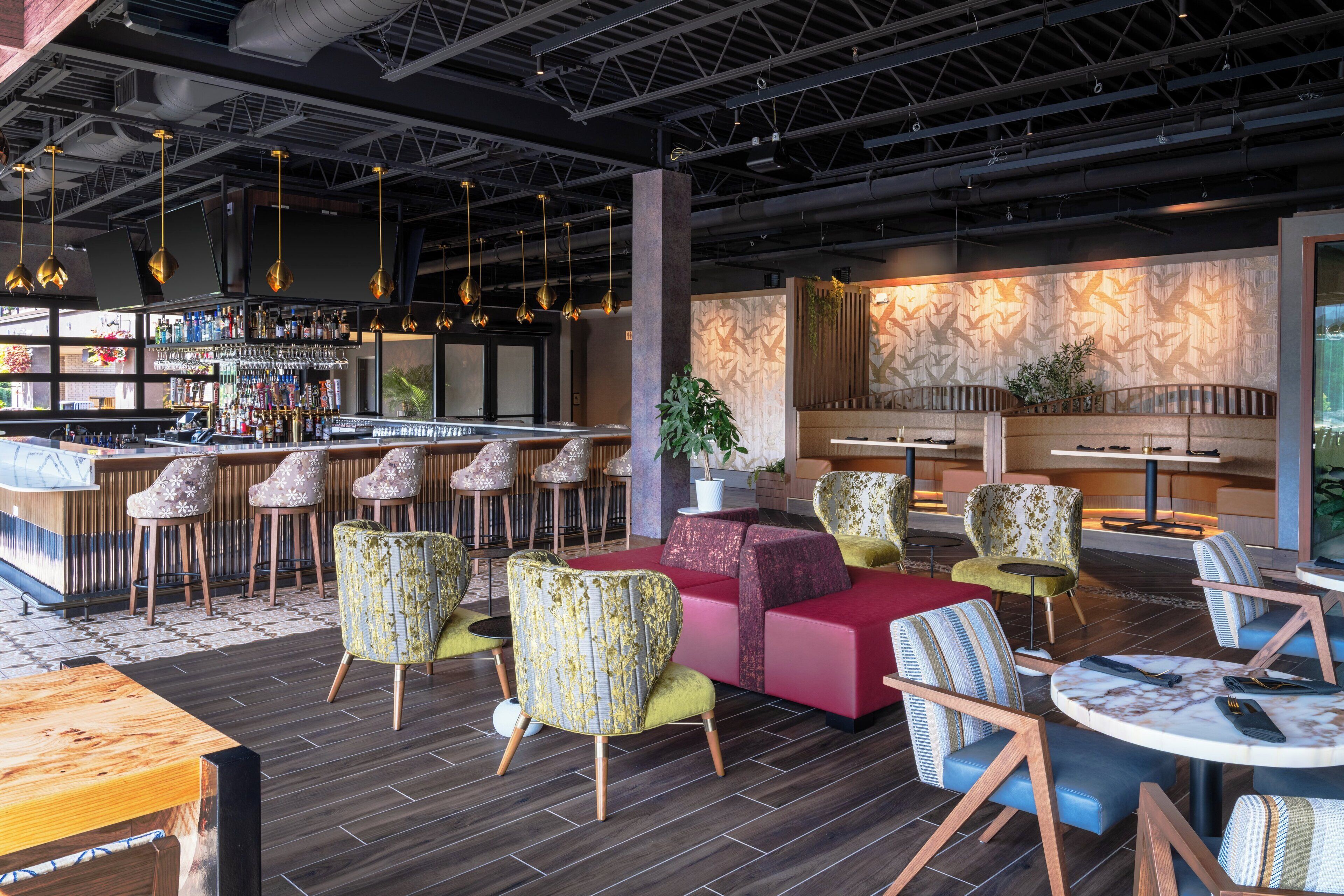 A modern bar area with a bar counter, multiple stools, and a seating area with sofas and chairs.