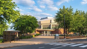 A modern building with a large entrance, a bus stop, and trees in front. - avid Hotel Bellefonte by IHG (Bellefonte)