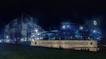 Una vista nocturna del campus de la Universidad Estatal de Pensilvania, con edificios iluminados y un cartel destacando.