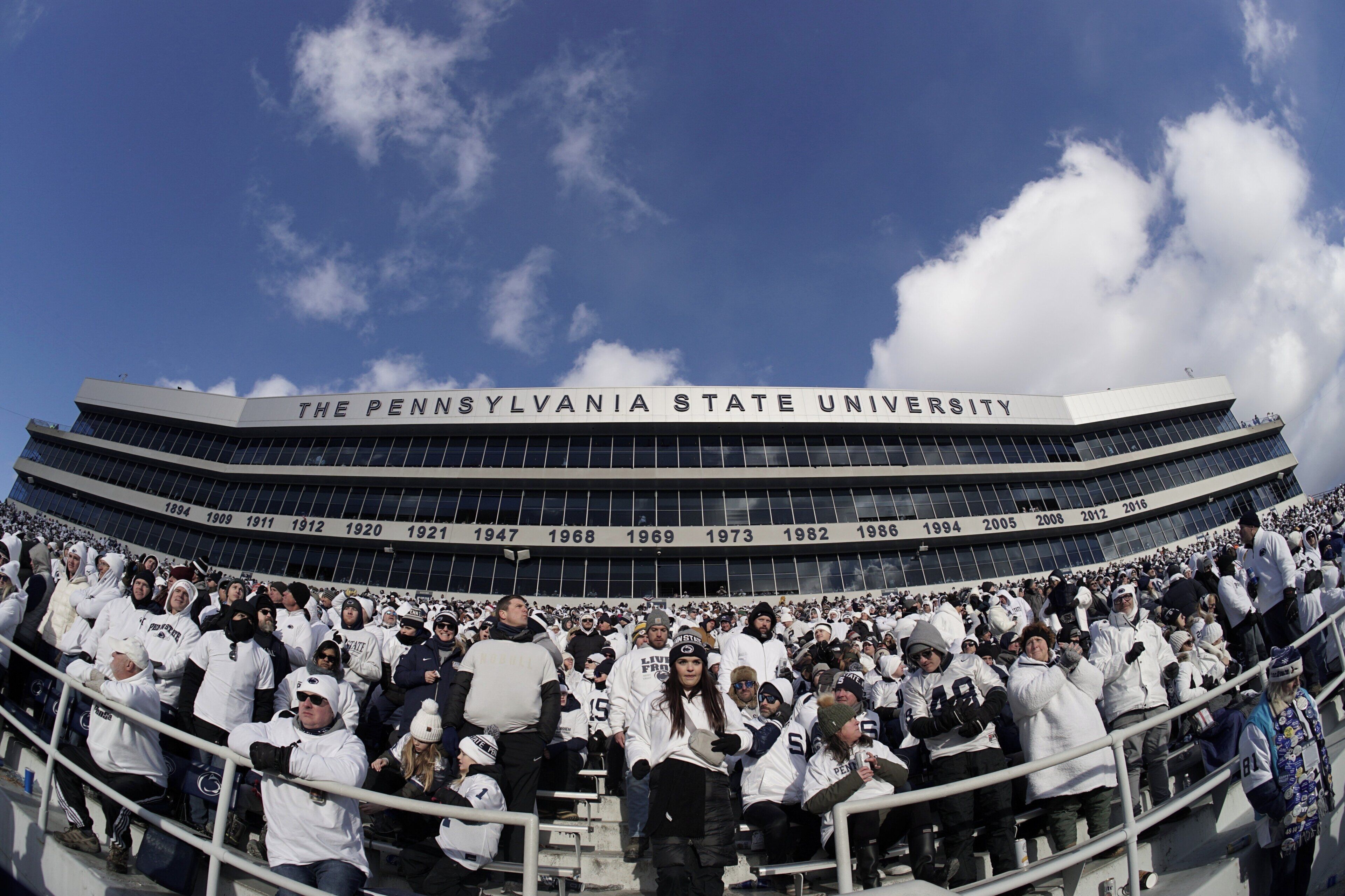A stadium with 'The Pennsylvania State University' signage, seating capacity numbers, and a crowd of spectators.