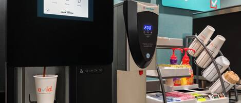 A coffee machine with a digital display, a cup holder, and a dispenser with various coffee pods.