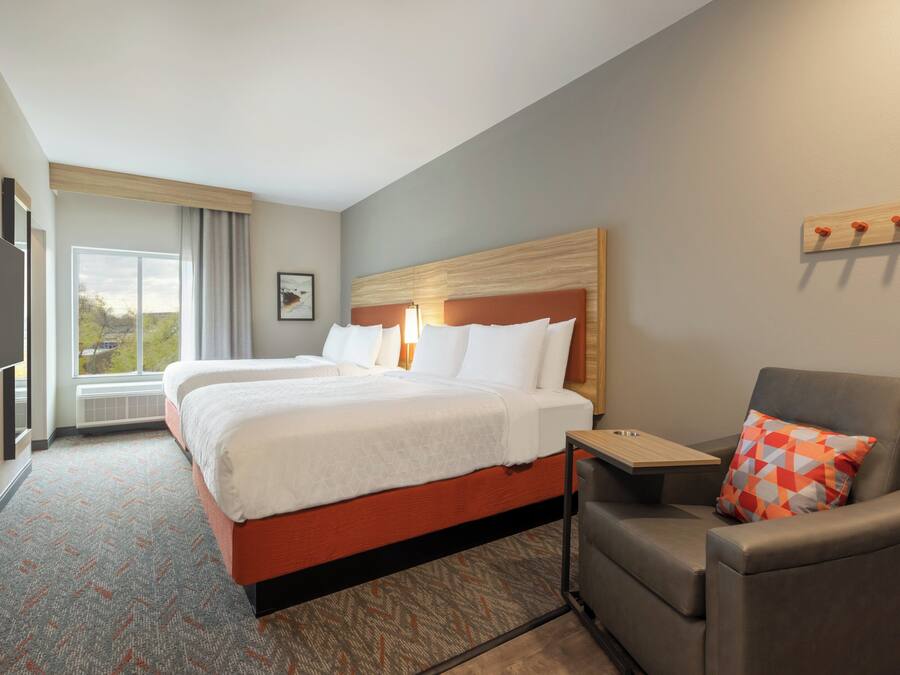 A hotel room with a large bed, a desk, a chair, and a television.