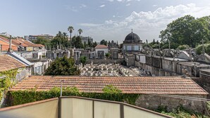 Un cementerio con lápidas y cruces, rodeado de edificios y árboles.