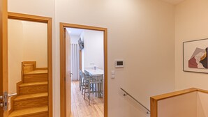 Un pasillo con escaleras de madera que conducen a un comedor con una mesa y sillas.