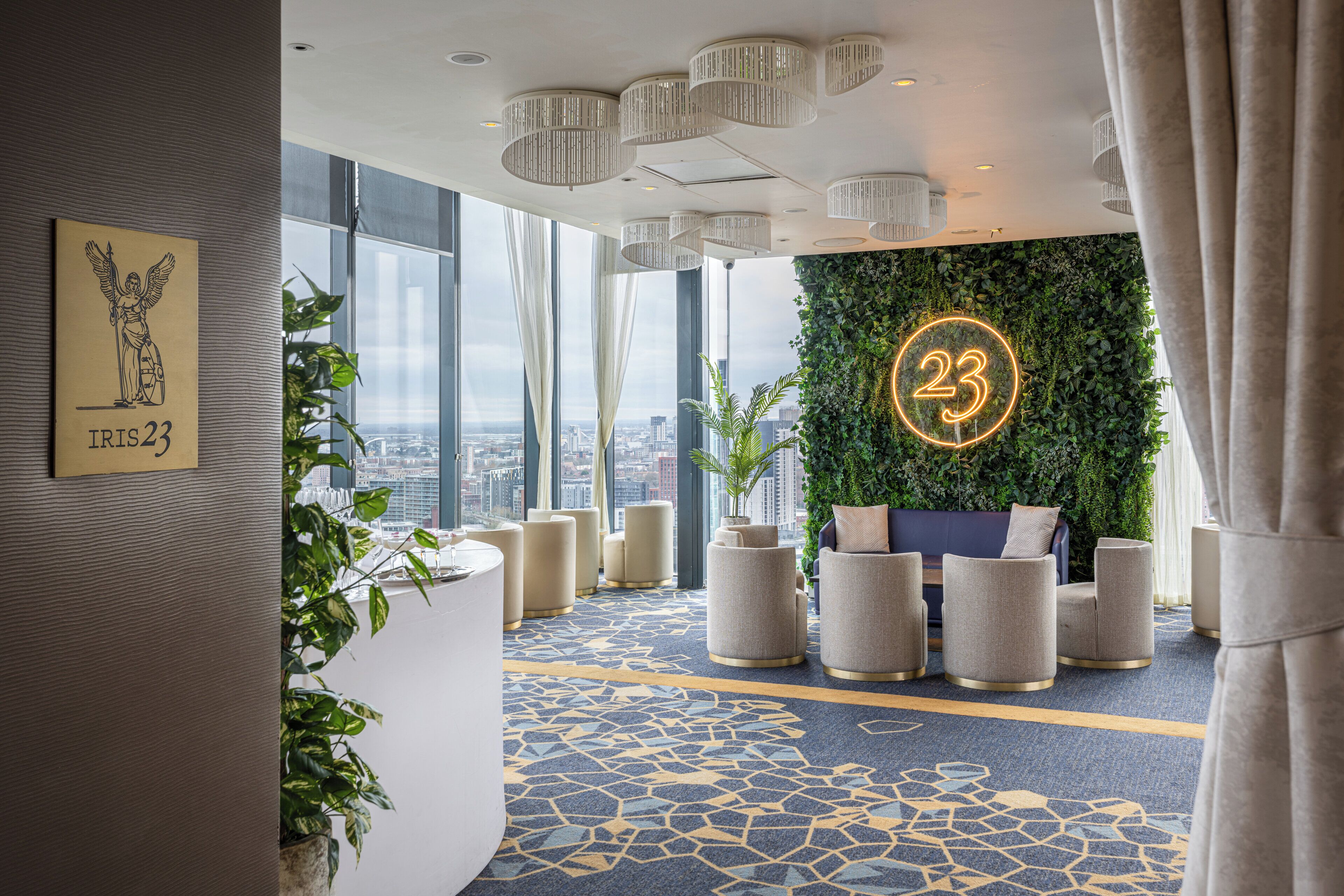 A modern lobby with a city view, a green wall with a neon number, and a patterned carpet.