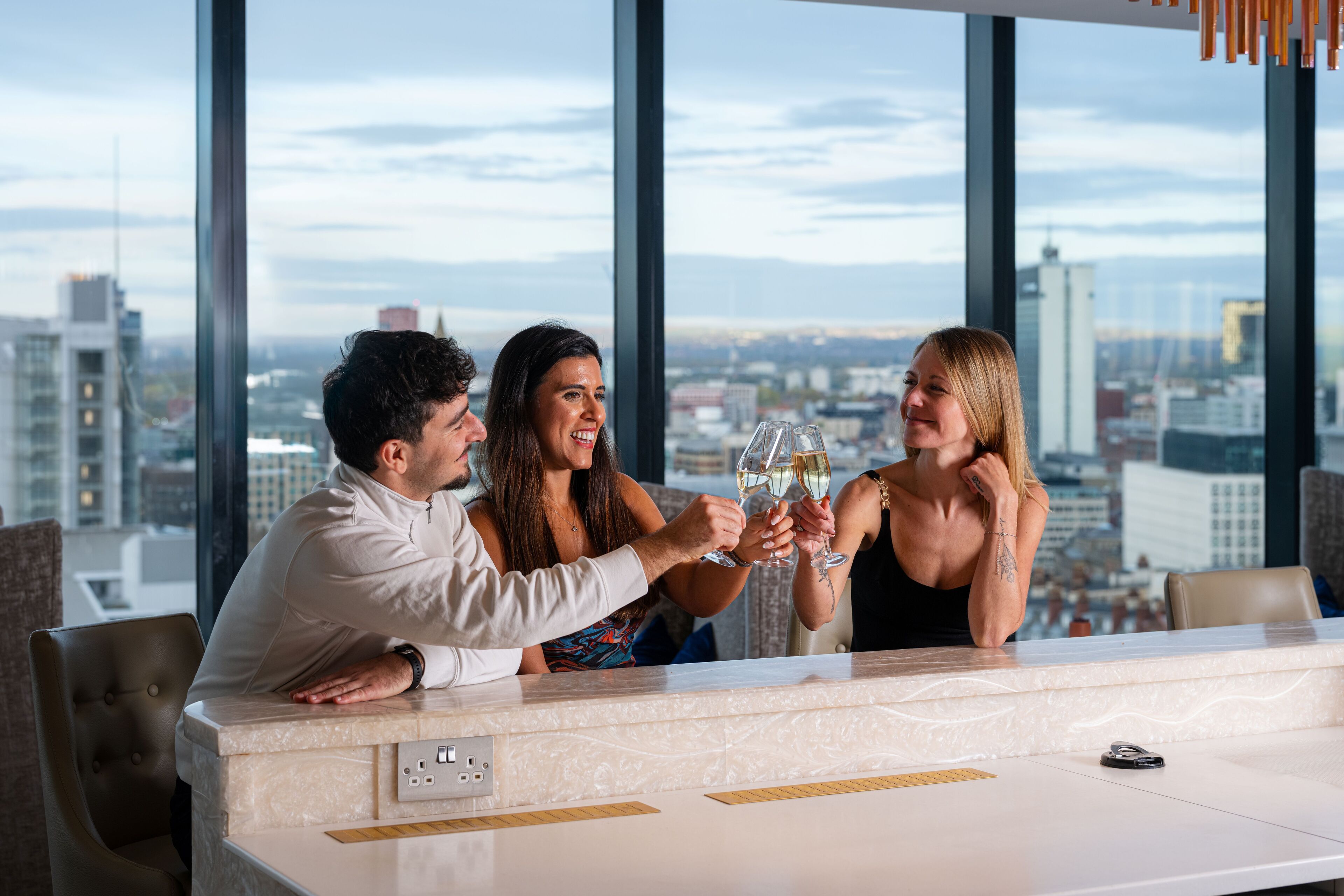 Un bar de hotel de gran altura con vistas a la ciudad, ventanas amplias y un diseño interior moderno.