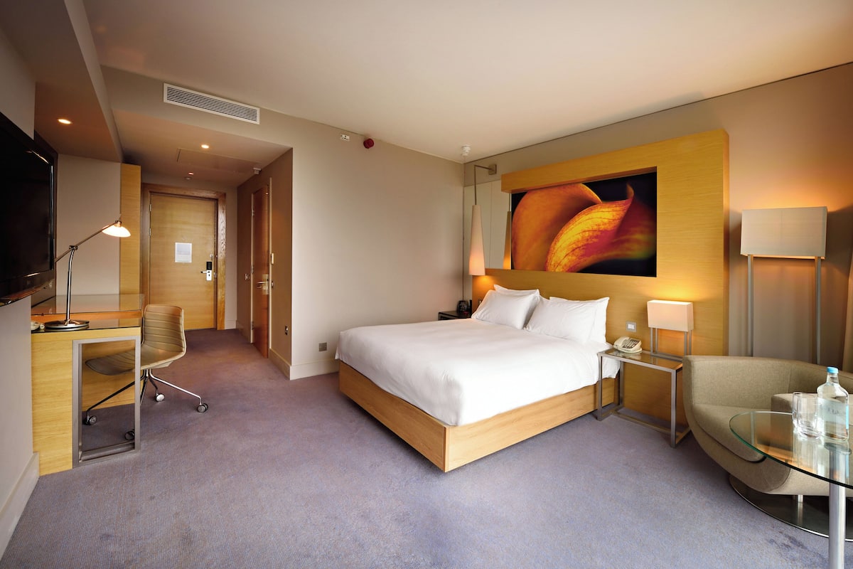 Een hotelkamer met een bed, nachtkastjes, een bureau, een stoel en een televisie.